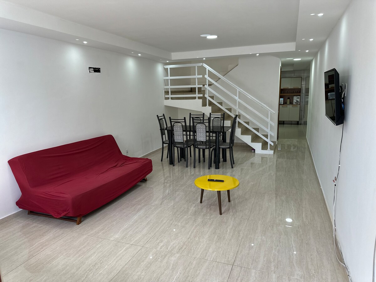 Sala ampla com sofá, mesa de jantar e escada